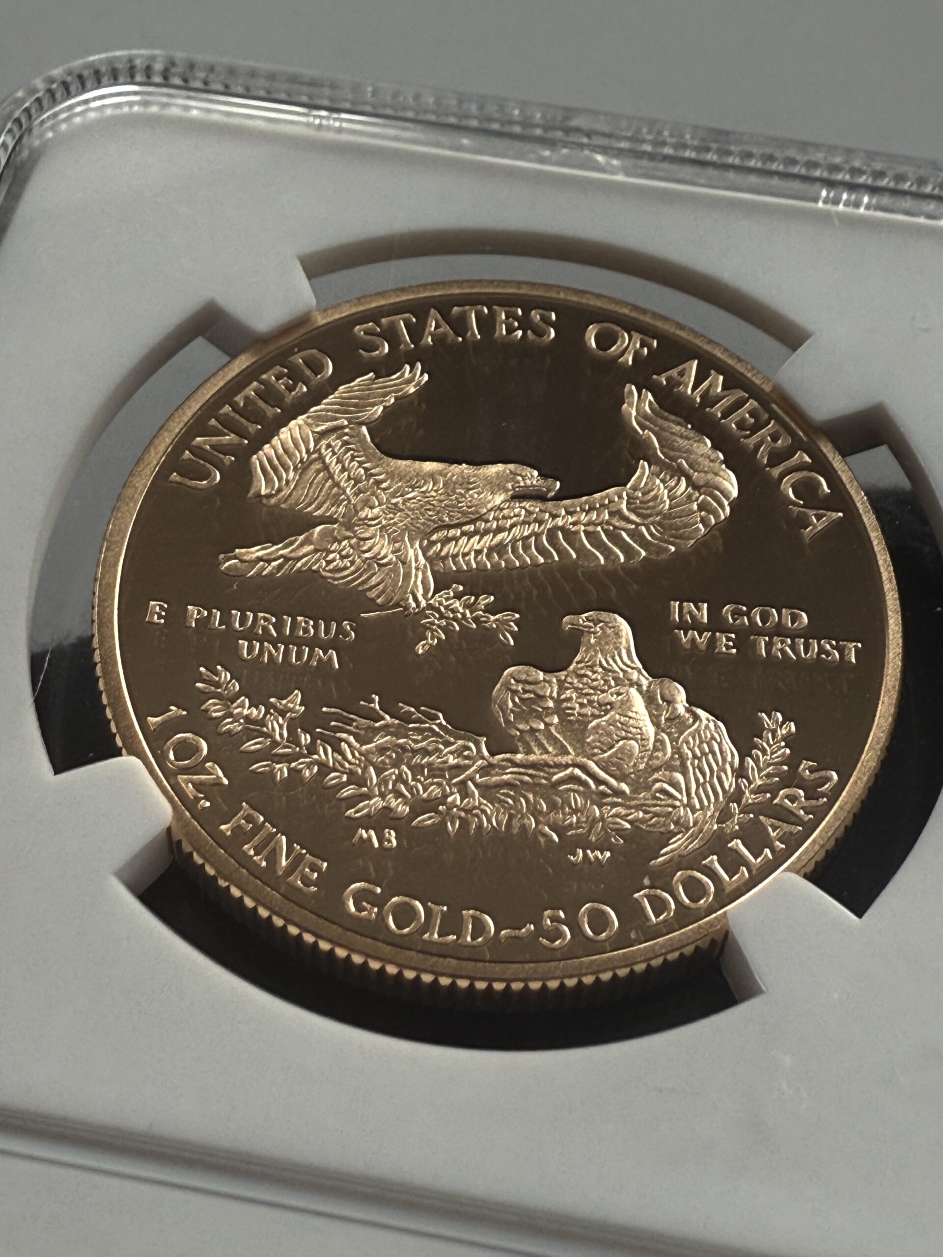 american-eagle-gold-proof-2012-50-us-dollar-1oz-gold-proof-ngc-pf70-ucam_4 USA 2012 American Gold Eagle 1 oz Proof im NGC-Slab PF70 UCAM; Schrägaufnahme der Rückseite mit Adlerfamilie und unten sichtbarem NGC-Hologramm.