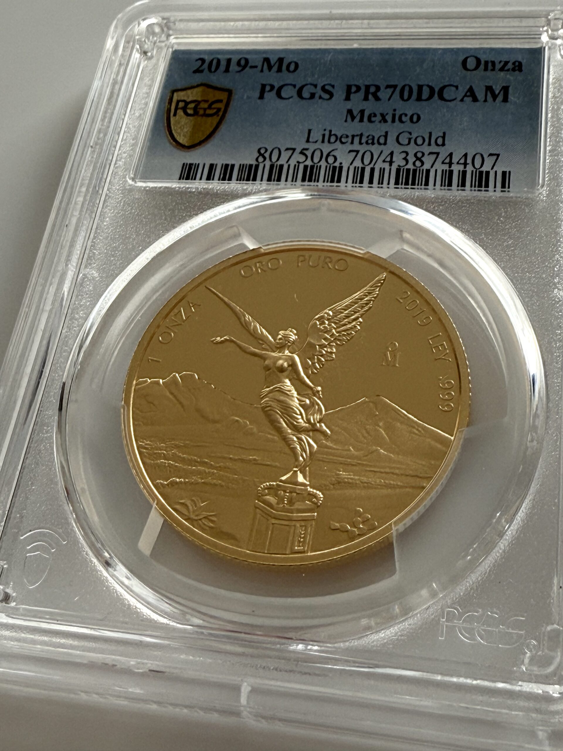 México-2019-Libertad-1-oz-Moneda-de-Oro-Prueba-PCGS-PR70-DCAM_1 México 2019 Libertad 1 Onza Gold Proof en losa PCGS PR70DCAM; Frente con Victoria (Ángel de la Independencia) frente a Popocatépetl e Iztaccíhuatl.