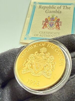 gambia-1996-200-dalasis-lowe-endangered-wildlife-1oz-gold-proof-mit-zertifikat_8 Gambia 1996 200 Dalasis Goldmünze Löwe Endangered Wildlife 1oz .999 Au Proof in transparenter Kapsel, COA der Republic of The Gambia im Hintergrund teilweise sichtbar.