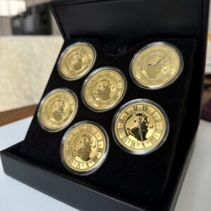 Kanada 2005 Zeit­zonen Kanadas Gold Proof Set – sechs 300-Dollar-Goldmünzen im geöffneten schwarzen Präsentationsetui, jede Münze gekapselt mit römischem Zifferblatt, Weltkarten-Motiv und unterschiedlichen Uhrzeiten auf schwarzer Velourseinlage.