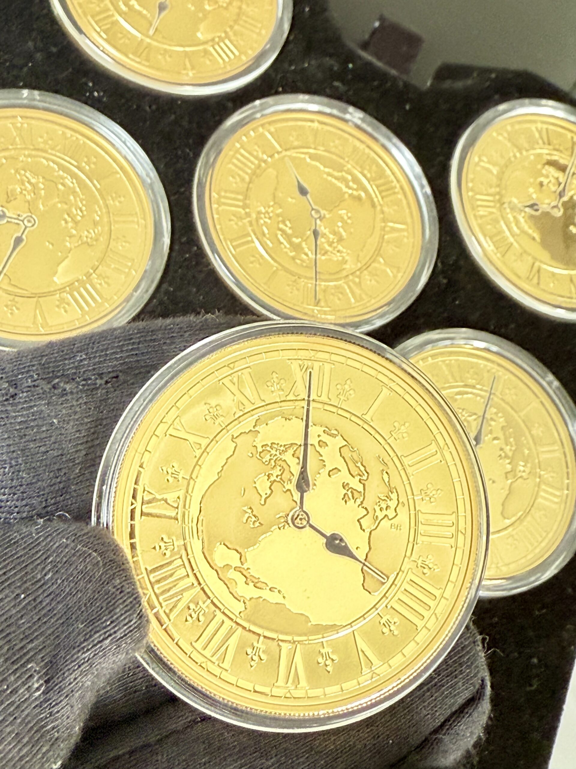 kanada-2005-300-dollar-zeitzonen-kanadas-5oz_10 Kanada 2005 Zeitzonen Kanadas Gold Proof Set – sechs 300-Dollar-Goldmünzen im geöffneten schwarzen Präsentationsetui, jede Münze gekapselt mit römischem Zifferblatt, Weltkarten-Motiv und unterschiedlichen Uhrzeiten auf schwarzer Velourseinlage.