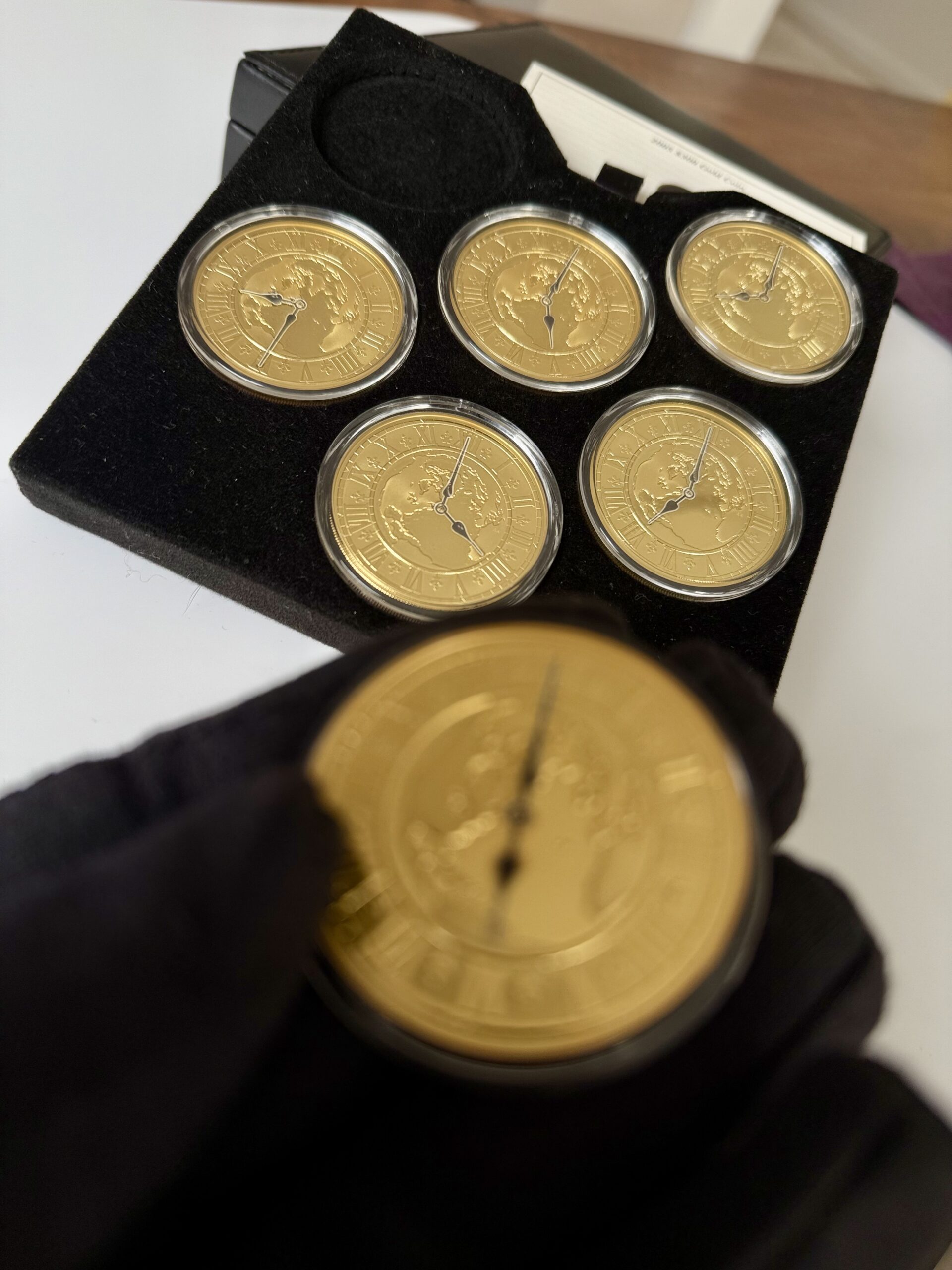 kanada-2005-300-dollar-zeitzonen-kanadas-5oz_6 Kanada 2005 Zeitzonen Kanadas Gold Proof Set – sechs 300-Dollar-Goldmünzen im geöffneten schwarzen Präsentationsetui, jede Münze gekapselt mit römischem Zifferblatt, Weltkarten-Motiv und unterschiedlichen Uhrzeiten auf schwarzer Velourseinlage.