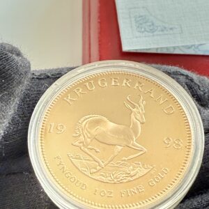 Krugerrand 1998 1oz Gold, Springbock-Seite, gekapselt vor roter Box, COA der South African Mint teilweise sichtbar.