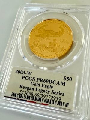 EE. UU. American Eagle Gold Proof 2003 50 dólares estadounidenses_3 EE. UU. 2003 American Eagle 1 oz oro Proof 50 dólares, Saint-Gaudens Liberty con antorcha y rama de olivo, año 2003 con W-Mintmark, en soporte PCGS con etiqueta de firma de Michael Reagan, fotografiada en ángulo.