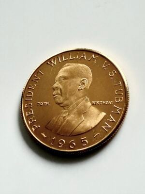 Pièce d'or de 12 dollars du Libéria, 1965, commémorant le 70e anniversaire du président William V.S. Tubman, sur fond blanc.