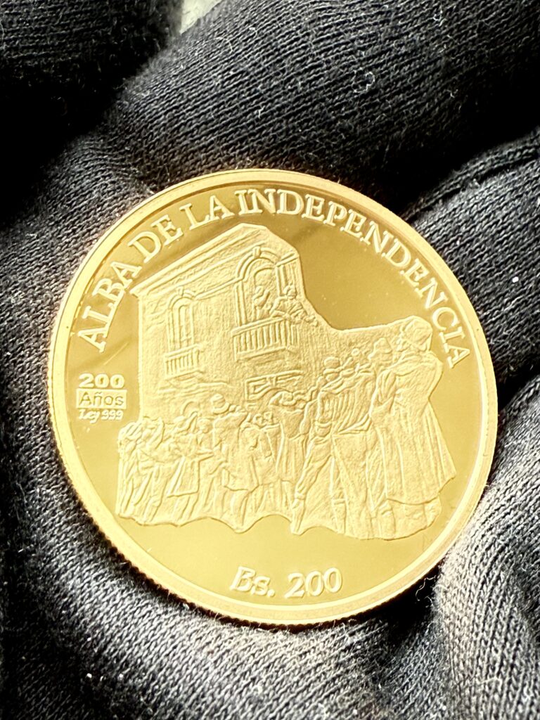 Venezuela 200 Bolívares Goldmünze „Alba de la Independencia“ auf schwarzem Handschuh