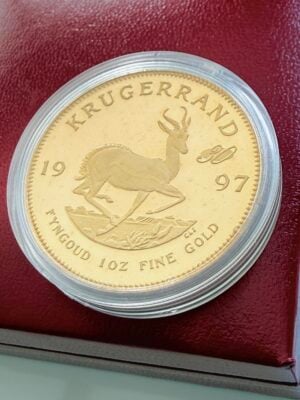 Moneda de oro Krugerrand de Sudáfrica de 1997 con marca de ceca de 30 años en su caja roja original, mostrada con el reverso y el motivo del springbok.