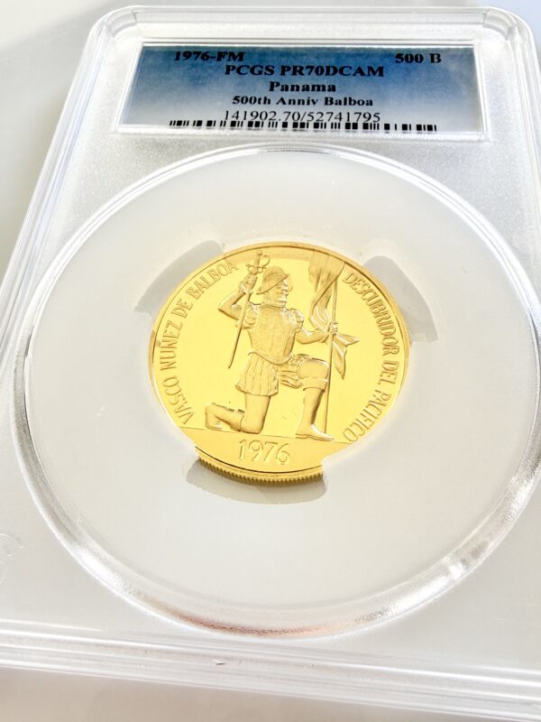PCGS-zertifizierte Goldmünze aus Panama von 1976. Das Label zeigt „1976-FM - 500 B - PCGS PR70DCAM - Panama - 500th Anniv Balboa“ sowie die Zertifizierungsnummer 141902.70/52741795. Die Münze ist in einem PCGS-Slab auf weißem Hintergrund fotografiert und zeigt Vasco Núñez de Balboa kniend mit Fahne.